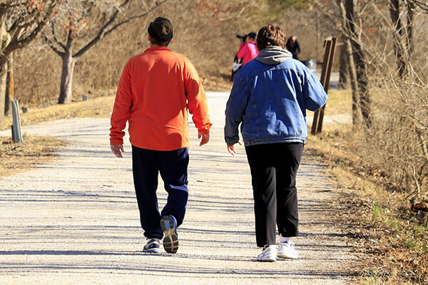 Overweight couple—concerned about risks associated with obesity—walking on a nature path