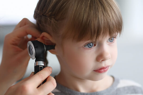 physician looking at little girl's ear infection.