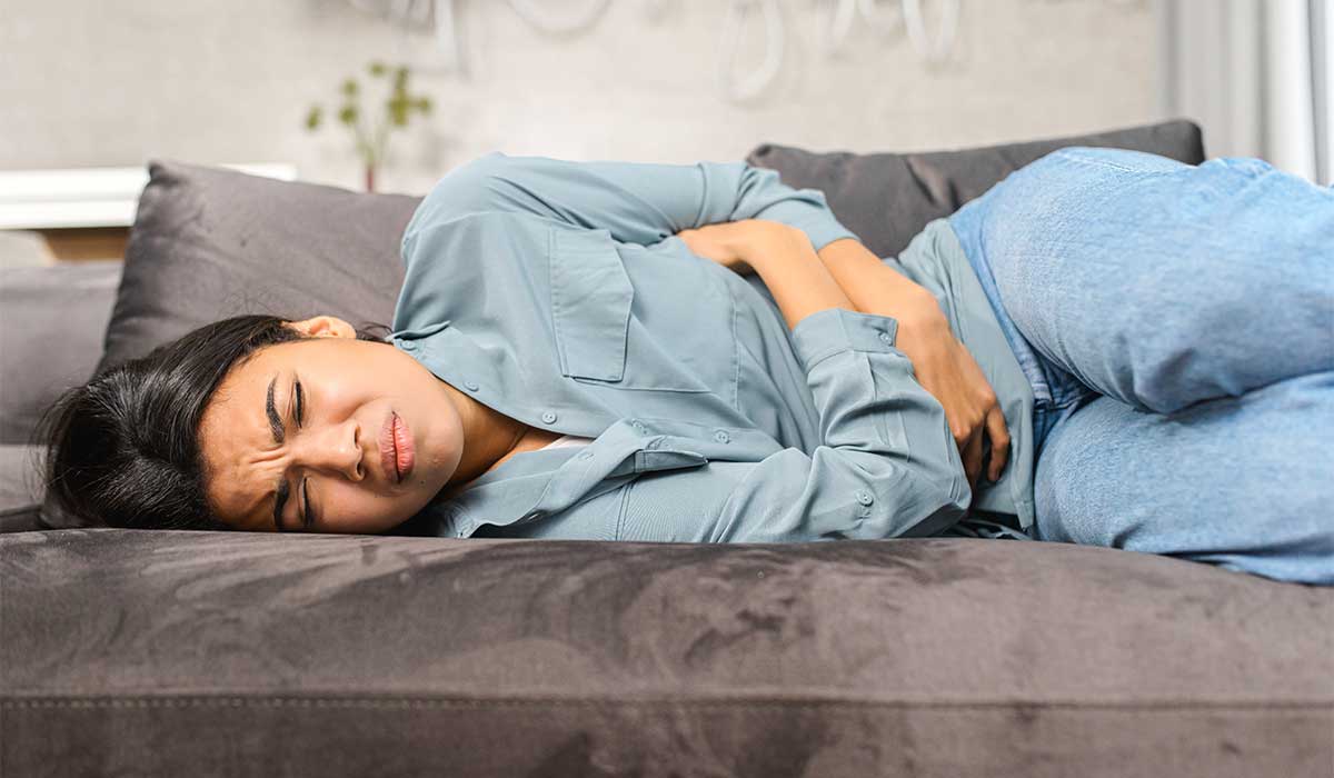 woman laying on couch in pain from appendicitis symptoms
