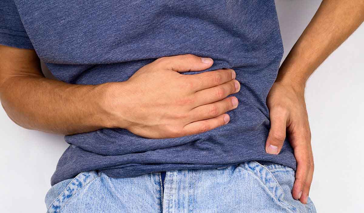 man holds stomach because of pain from gallbladder disease